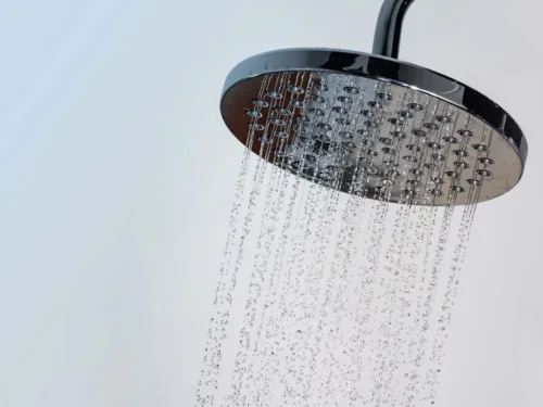 A chrome shower-head with water running.