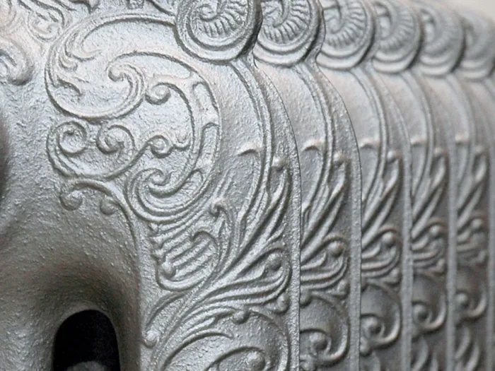 A close-up of a ornate, cast-iron radiator with embossed swirling patterns.