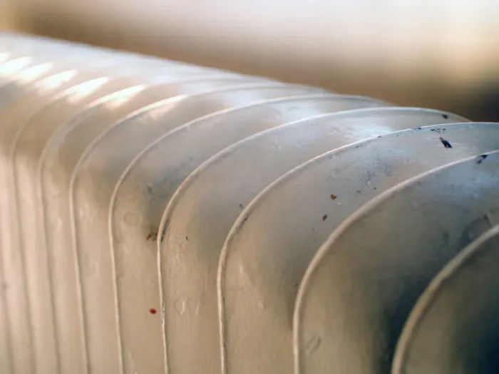 A close-up of a white, finned radiator.