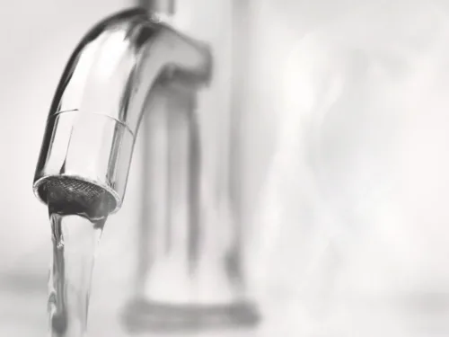 A chrome faucet with water running.