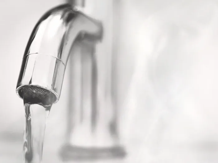 A chrome faucet with water running.